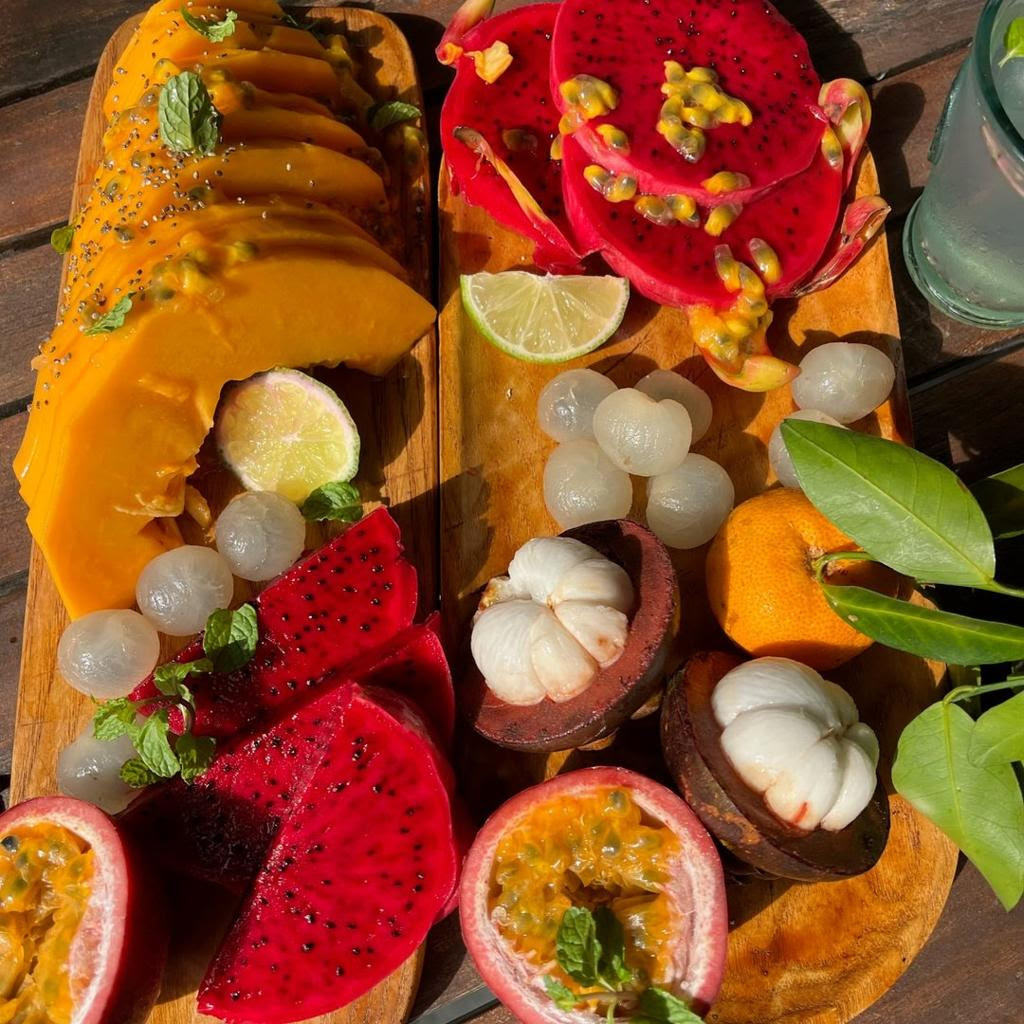 A wooden board of tropical fruit including dragon fruit, passion fruit and mango